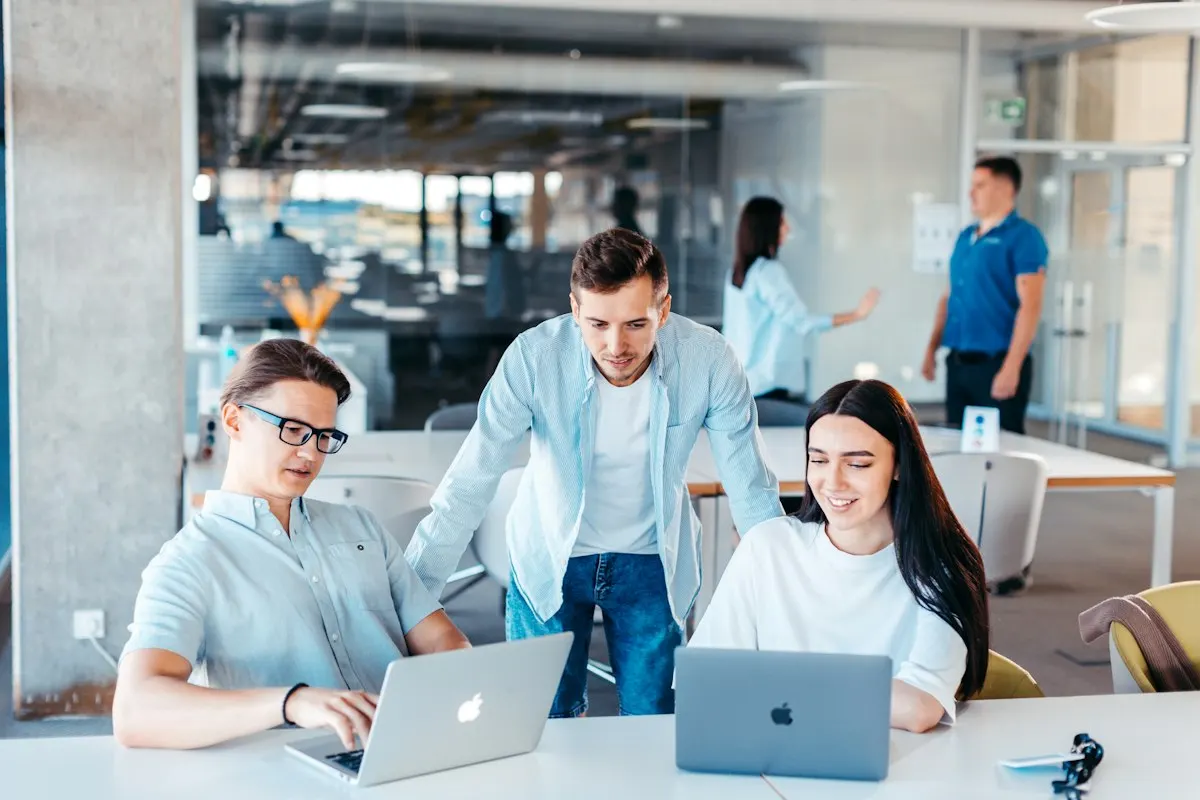 Jeune équipe réunie autour d'ordinateurs portables dans un espace de travail