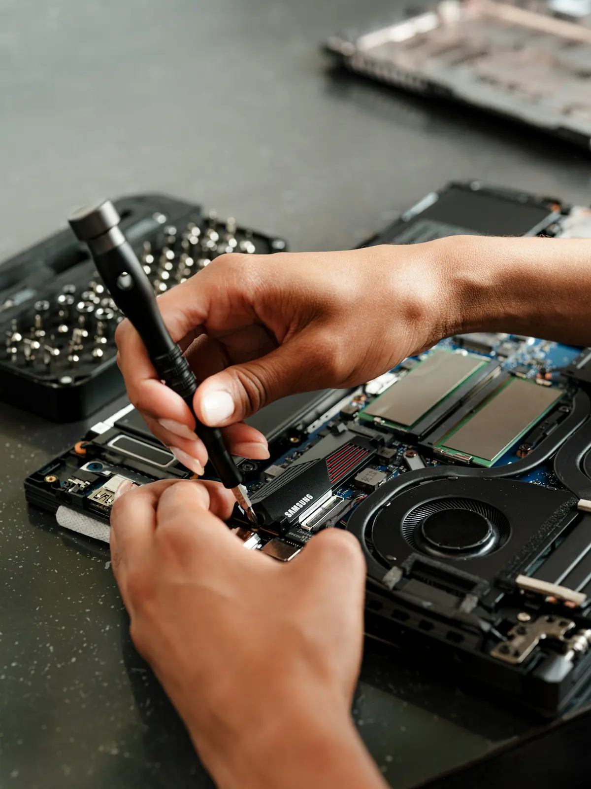 Réparation d'un ordinateur portable, mains d'un technicien avec un tournevis